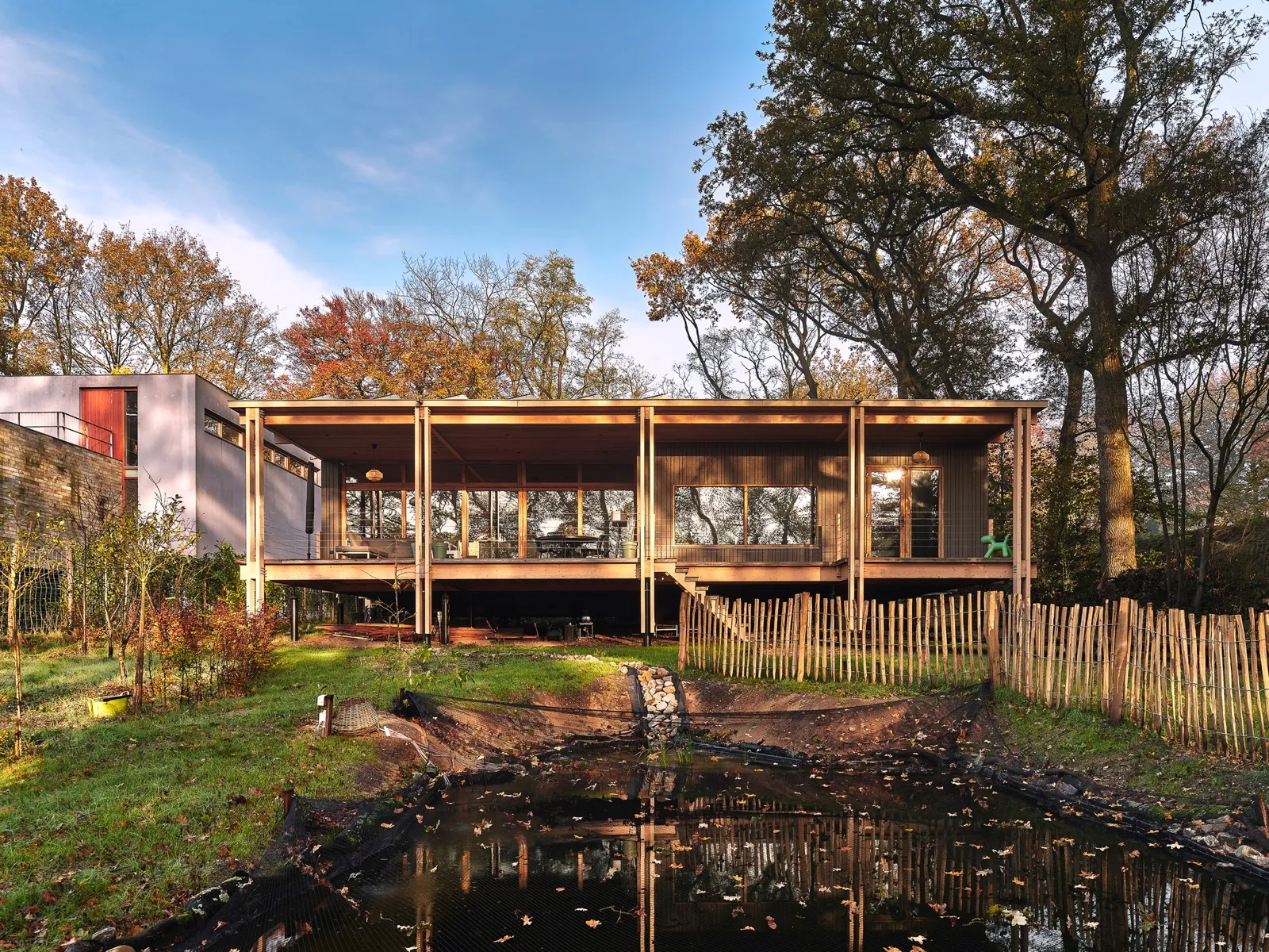 Houtbouwvilla in Renkum met zichtbare houten draagconstructie, weerspiegeld in de vijver