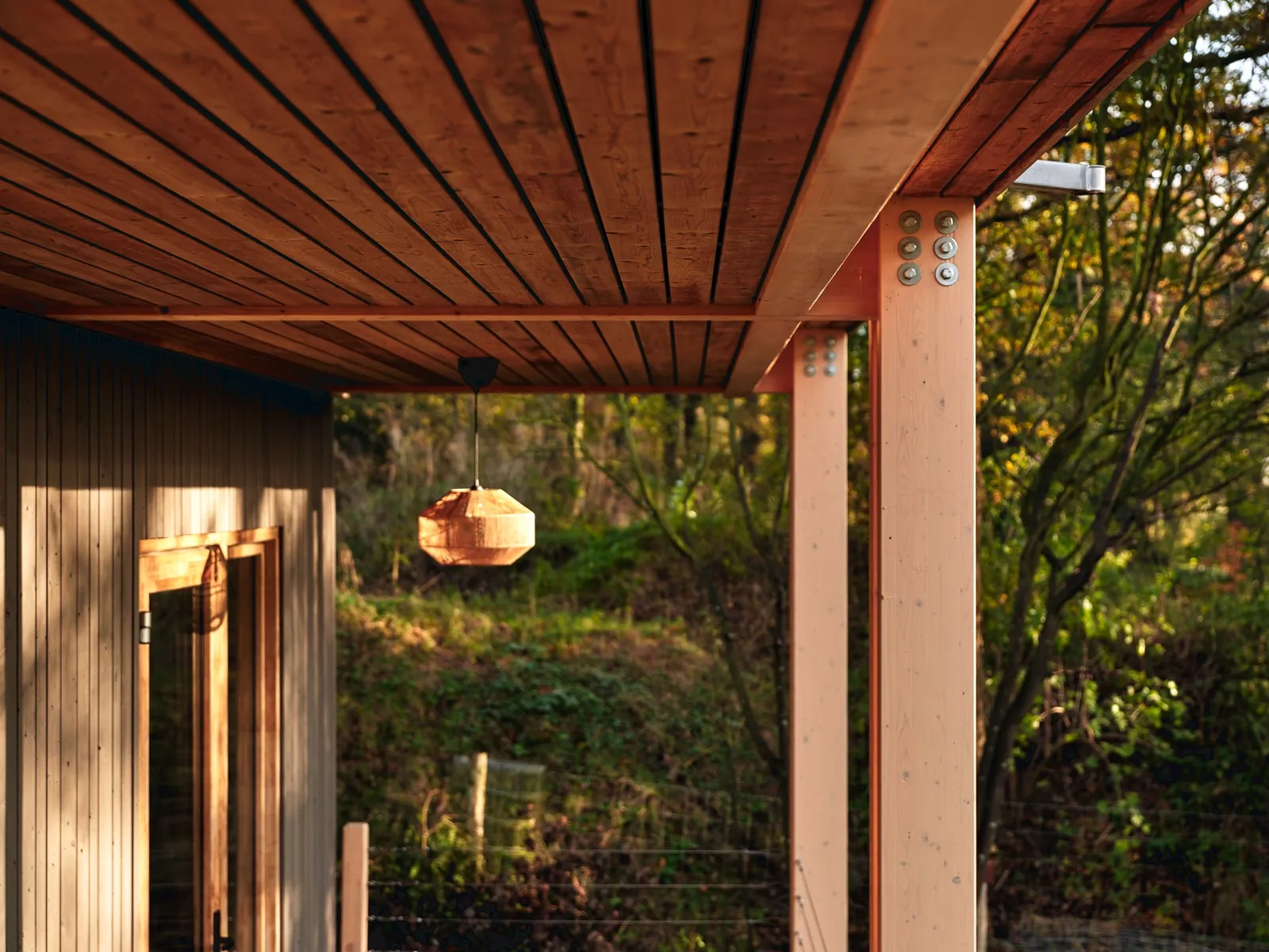 Detail van een houten ligger met houten latten-plafond en stalen verbindingsstuk